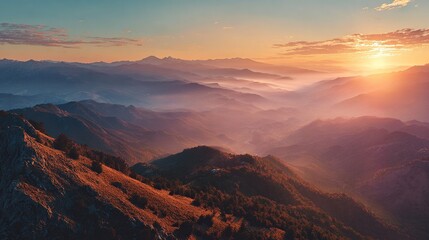 A scenic vista of layered mountain ranges at sunrise, bathed in warm light and soft clouds