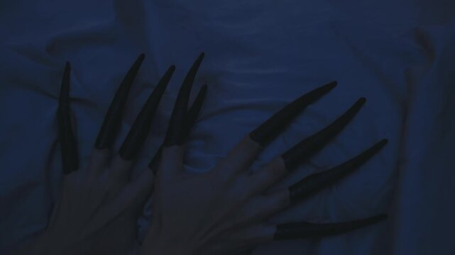 close-up body part scary ghost hand with long black nails scratching wall. nightmare monster in dark home room bedroom fingers evil demon witch. vampire searching for victim. Night flashes lightning