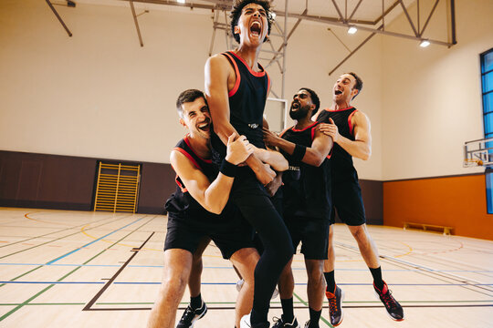 Basketball team passionately celebrating huge victory on court - Powered by Adobe
