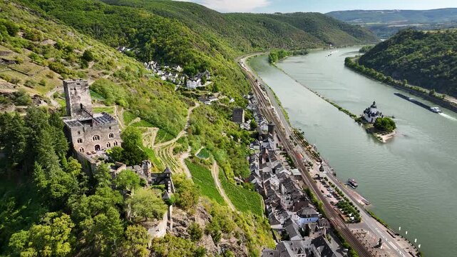 Aerial footage over the Rhine Valley with medieval hillside castle Gutenfels, vineyards, town of Kaub and Pfalzgrafenstein Castle located on a small island in the river.