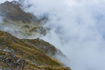 mountain landscape with fog on sharp ridge on autumn day