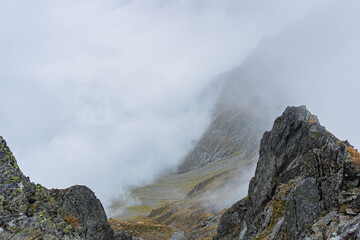 mountain landscape with fog on sharp ridge on autumn day