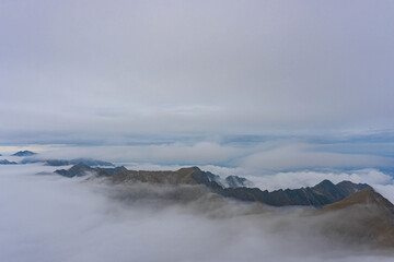 view of highest peaks of romanian carpathian ridge chain from top on very cloudy day with fluffy white clouds at bottom