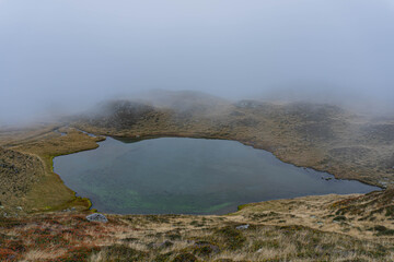fog in the mountains and glacier lake on autumn moody day 