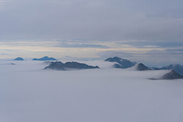view from moldoveanu of highest peaks of romanian carpathian ridge chain from top on very cloudy day with fluffy white clouds at bottom