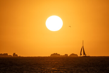 Sailboat at sunset with a few rocks in the background