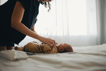 Mother cares for baby on bed in natural light