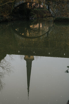 View of the reflection of a church steeple piercing the still water, mirroring the arched bridge above, in the heart of Luxembourg City, Luxembourg City, Luxembourg.