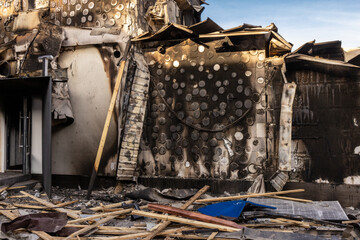 War. The aftermath of Russian airstrikes on a peaceful Ukrainian city. A hospital and a recreation center were destroyed. Charred wall with circular burn marks and debris from fire damaged building.