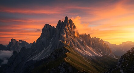 Jagged mountain peak glows at sunrise dramatic ridges and misty slopes winding trail through grassy hills vibrant sky in orange and purple tones
