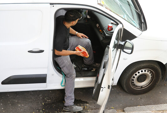 Hora del bocadillo emparedado de chorizo, receso, refresco de cola y descanso para trabajador en asiento de furgoneta blanca en la calle