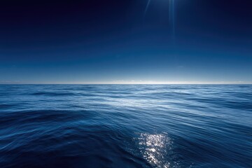 A vast, serene expanse of blue ocean stretches toward a brilliant sunlit sky, minimal detail