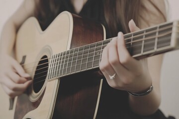 Fototapeta premium A person's hands are expertly shown playing an acoustic guitar. Fingers press frets and strum the strings, creating a beautiful melody.