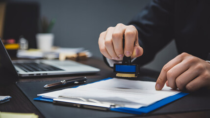 Successful businessman officially stamping document in modern office, ensuring compliance and legal approval for important corporate agreement today
