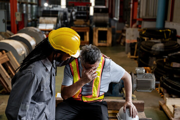 A man in a yellow helmet and a man in a grey shirt are sitting on a bench