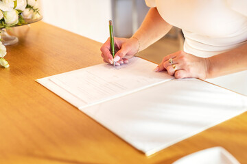 A woman signs a marriage contract with a pen at an office or church. Confirmation of a surname change by signature at a wedding day