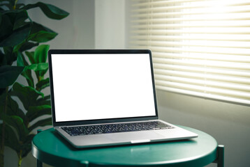Laptop mockup with blank white screen on a green round table in window light. home office scene for UI previews, web banners, presentations, and product marketing.