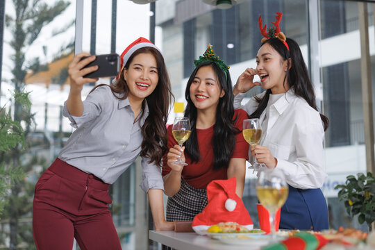 Women taking selfie celebrating office christmas party