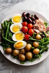 Classic French Niçoise salad with tuna, potatoes, beans, eggs and olives on white dinner plate