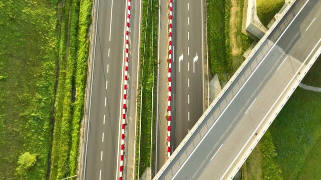 Extreme top-down aerial shot highlighting the geometric layout of an S6 expressway overpass and the lanes separated by red and white safety barriers.