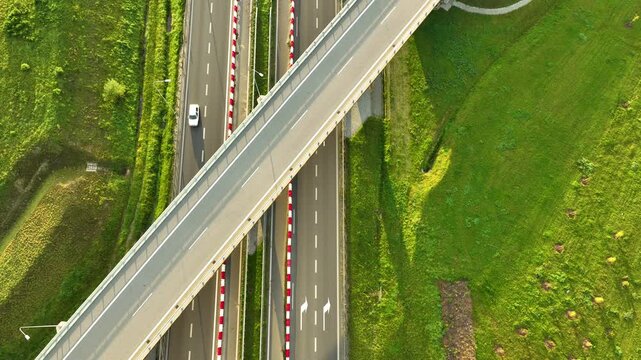 Striking top-down aerial view of a modern highway overpass intersecting the S6 expressway lanes, showcasing the geometry, with a single white car below.