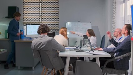 A professional business meeting in a modern office. The manager uses a pointer to explain charts on a monitor to a group of colleagues seated with laptops. Collaborative and focused corporate - Powered by Adobe