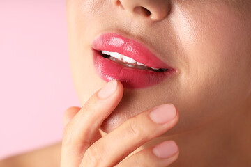Obraz premium Woman with beautiful lipstick on her lips against pink background, macro view