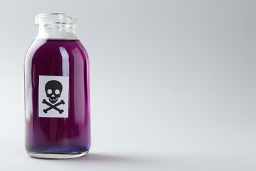 Bottle of poison with warning sign on light background. Space for text