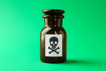 Bottle of poison with warning sign on green background, closeup