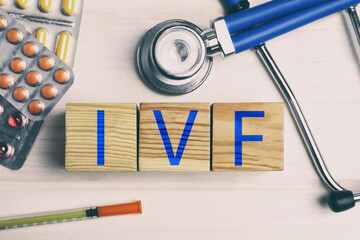 In vitro fertilization. Wooden cubes with abbreviation IVF, pills, syringe and stethoscope on...