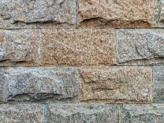 close-up of a rough-textured light brown natural stone wall that highlights the natural texture and veining of the rock, with the grout lines appearing thin and tight