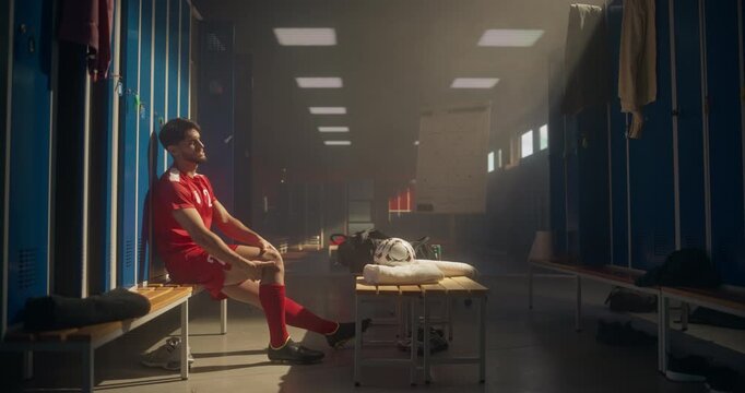Young Football Player Sitting on the Bench, Grimacing while Supporting His Injured Leg. Locker Room Scene Captures the Tension and Concern After a Painful Moment on the Soccer Field