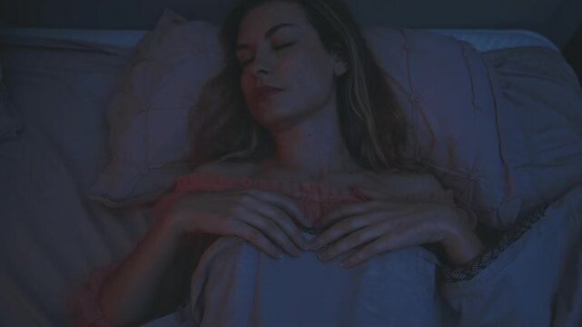 beautiful young woman lying in bed ghost pulling the blanket off sleeping person evil demon witch in night dark room flashes lightning storm rain. adult girl has nightmare sleeps paralysis bad dream