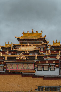 View of the golden roofs of the Songzanlin Monastery stand majestically against the overcast sky, a testament to ancient architecture, Di Qing Zang Zu Zi Zhi Zhou, Yun Nan Sheng, China.