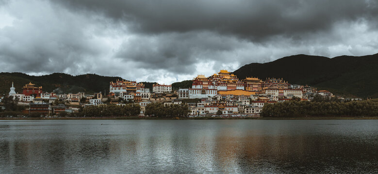 View of the Songzanlin Monastery reflecting in the still lake waters under a brooding sky, Di Qing Zang Zu Zi Zhi Zhou, Yun Nan Sheng, China.
