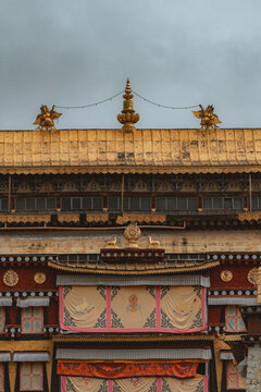 View of a traditional building featuring a golden roof adorned with intricate detailing and ornate decorations against a cloudy sky, Di Qing Zang Zu Zi Zhi Zhou, Yun Nan Sheng, China.