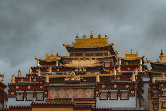 View of the golden roofs and intricate red details of Songzanlin Monastery against a moody sky create a striking image, Di Qing Zang Zu Zi Zhi Zhou, Yun Nan Sheng, China.