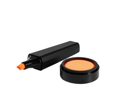 A black highlighter with its cap off near an orange ink pad on a dark background