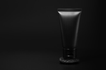 Black plastic cream tube with stone for mockup on black background. Selective Focus.