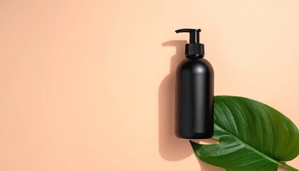 Obraz premium Black bottle on leaf, peach background. Shadow details