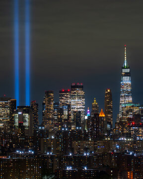 Tribute in Light. View of luminous twin beams pierce the night sky over a sprawling cityscape, reflecting off modern skyscrapers in solemn remembrance of 9-11, New York, New York, United States.