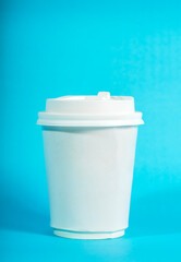 Blank white disposable coffee cup for mockup purposes. The to-go paper cup is isolated on a bright blue background, ready for your branding and logo design
