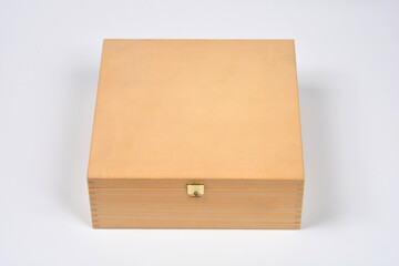 An overhead studio shot of a light wooden box featuring a small brass clasp
