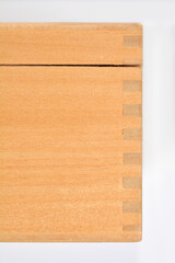 A close-up studio shot highlights the precise dovetail joinery at the corner of a light wooden box