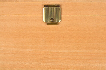A close-up, centered studio shot focuses on the decorative brass clasp on the lid of a light wooden box