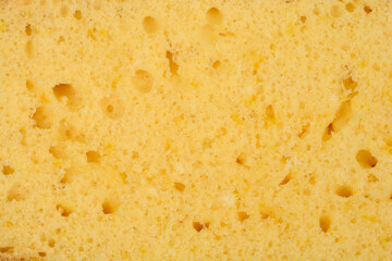 A full-frame, close-up shot captures the porous, golden-yellow texture of a freshly baked lemon sponge cake