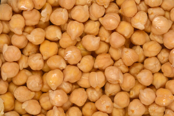 A close-up, full-frame shot shows a dense, light-tan texture of chickpeas soaking in water for preparation