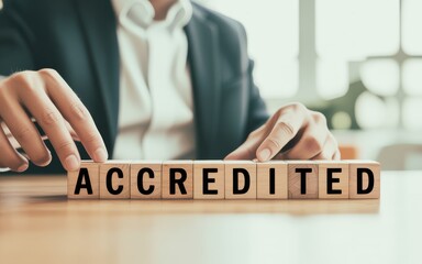 Obraz premium A businessman in a suit arranges wooden blocks to spell the word accredited, representing certification, quality standards, and official validation
