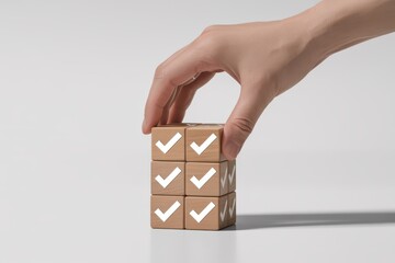 Woman's hand arranging wooden cubes with check marks, symbolizing the successful completion of a project checklist