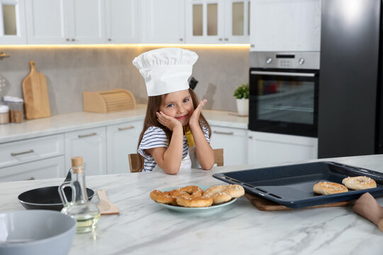 Choice of profession. Little girl with pastries pretending to be chef in kitchen